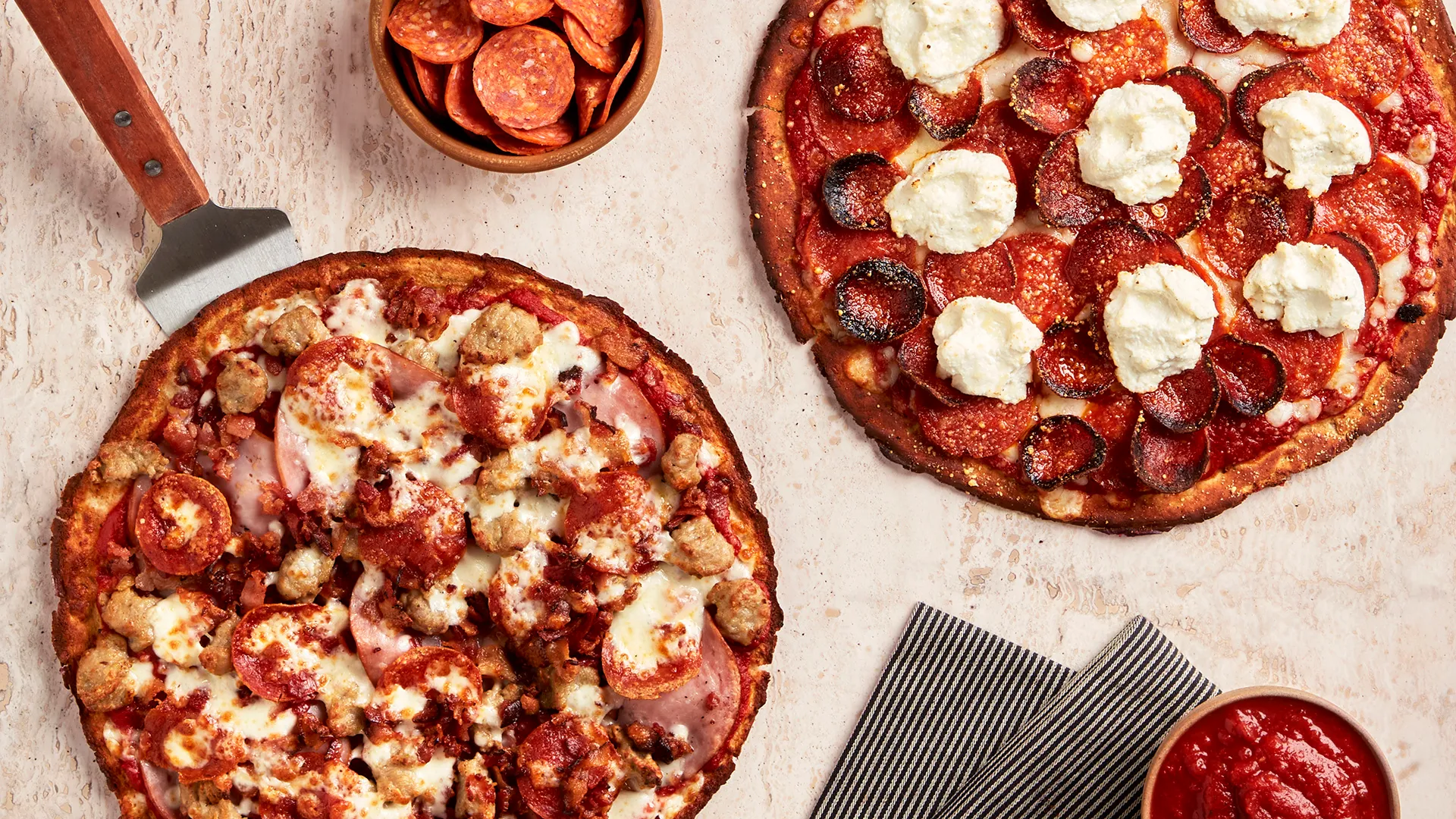Two Fresh Brothers pizzas, one loaded with sausage, bacon and pepperoni, the other topped with pepperoni and ricotta